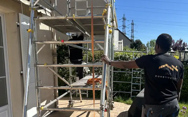 Échafaudage roulant monté sur la terrasse carrelée, le long de la façade